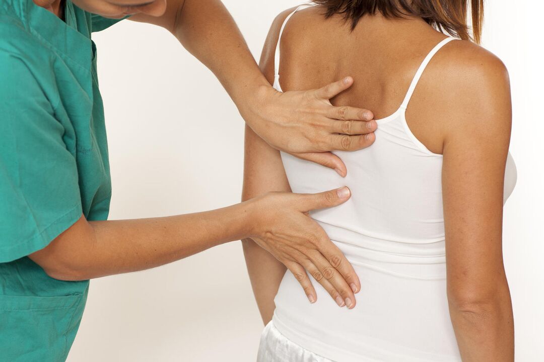 El médico examina la espalda en busca de dolor en los omóplatos.